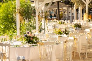 Beautifully arranged outdoor wedding reception with floral centerpieces and white decor.